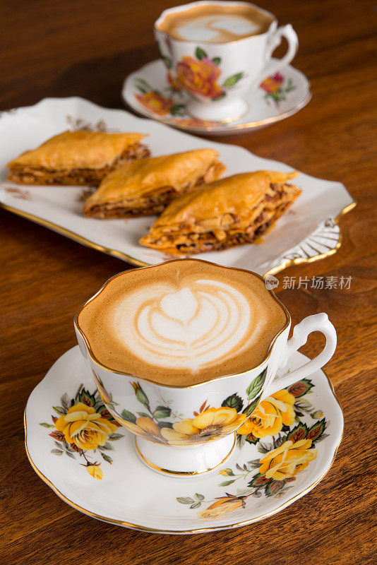 Cortado /平底白咖啡在一对20世纪60年代玫瑰图案骨瓷杯与果仁蜜饼的背景